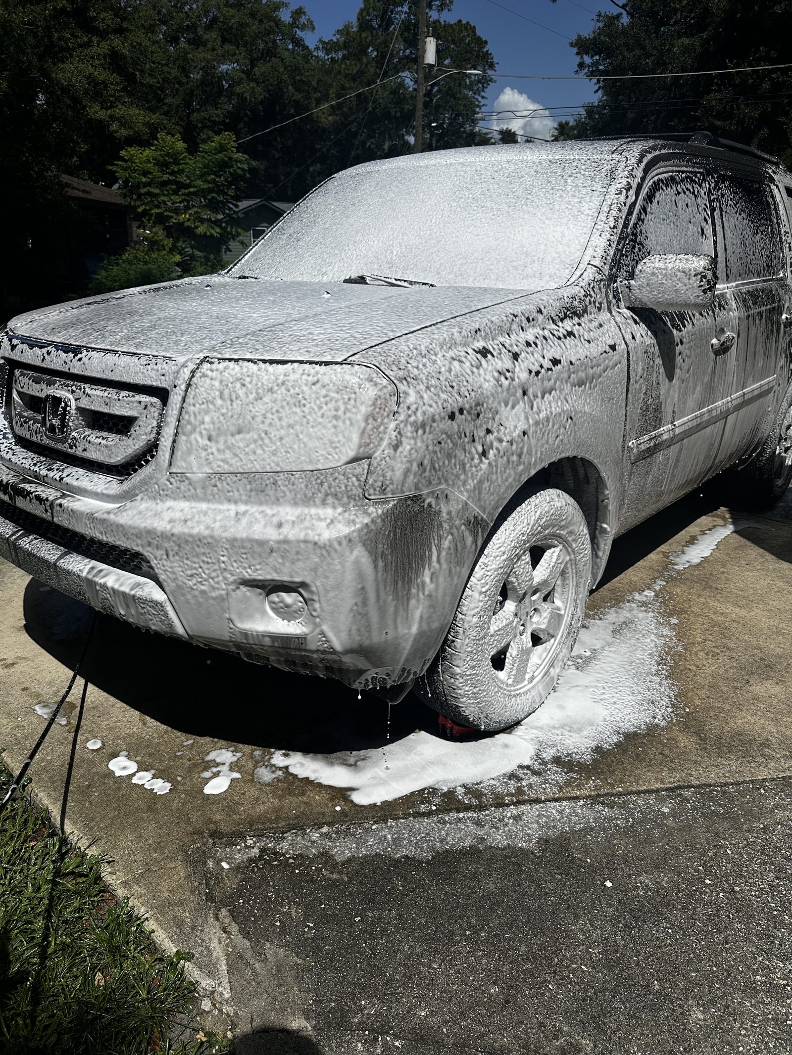 Gray Toyota Tacoma covered in thick snow foam during an exterior hand wash